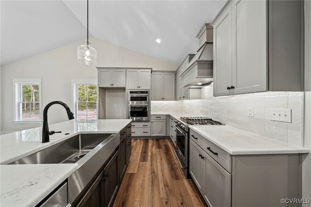 kitchen featuring gray cabinetry, dark wood-type flooring, light stone counters, stainless steel appliances, and lofted ceiling