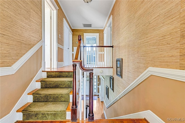 staircase featuring wooden walls and crown molding