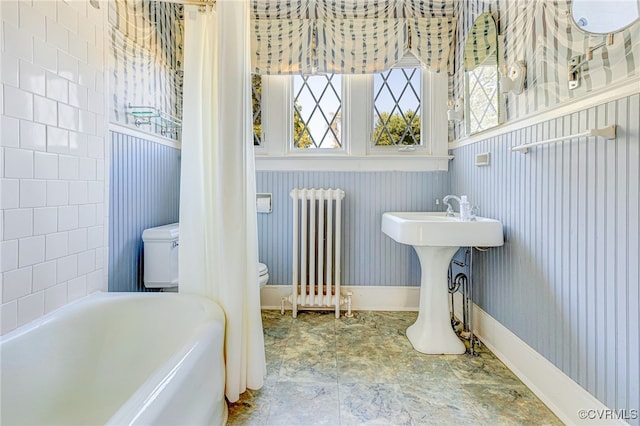 bathroom with radiator, a wealth of natural light, toilet, and a tub