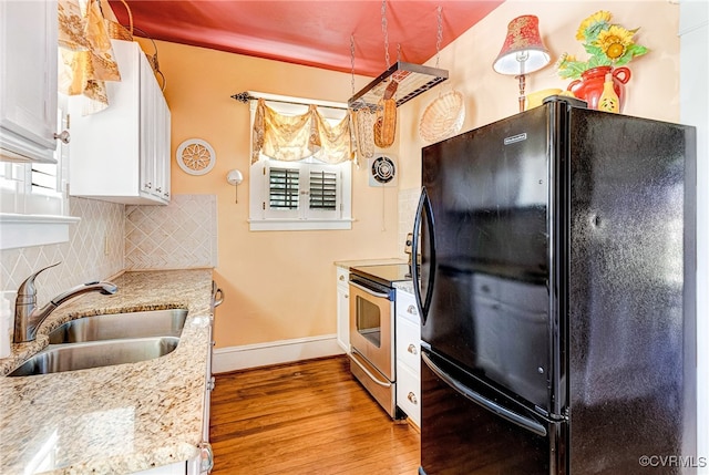 kitchen with white cabinets, backsplash, black refrigerator, sink, and stainless steel electric range oven