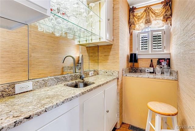 kitchen with light stone countertops, white cabinetry, plenty of natural light, and sink