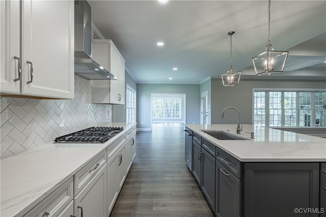 kitchen with a kitchen island with sink, sink, white cabinetry, wall chimney exhaust hood, and appliances with stainless steel finishes