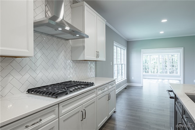 kitchen featuring backsplash, white cabinetry, wall chimney range hood, and light stone counters