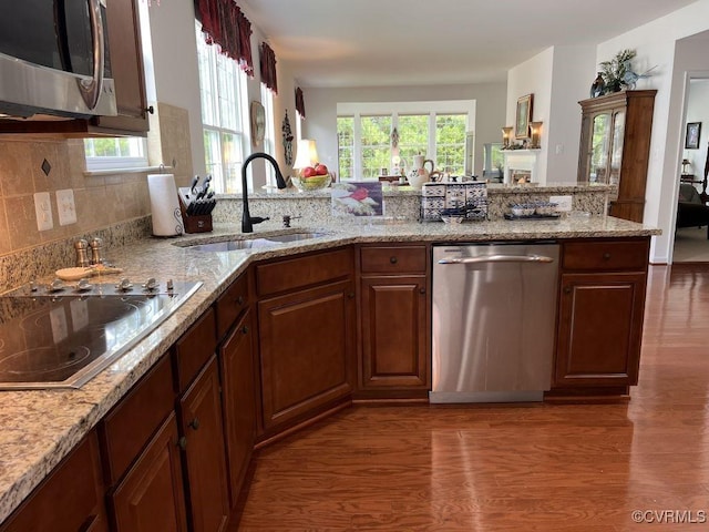 8232 E Lord Botetourt Loop, New Kent, VA 23124 - kitchen featuring light stone counters, a sink, appliances with stainless steel finishes, wood finished floors, and backsplash