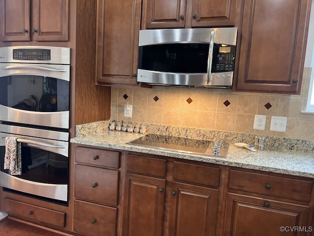 kitchen featuring decorative backsplash, light stone counters, appliances with stainless steel finishes, and dark hardwood / wood-style floors