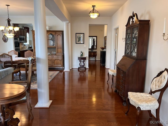 foyer entrance featuring dark hardwood / wood-style floors, ornate columns, and a chandelier