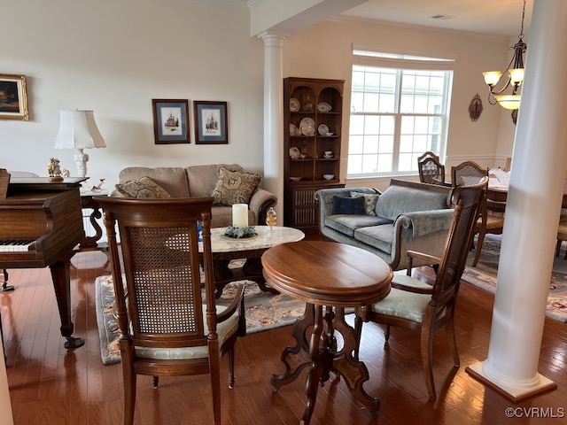 dining room featuring wood-type flooring, decorative columns, and a notable chandelier