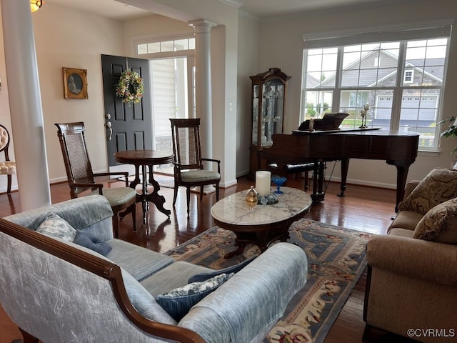 living room featuring hardwood / wood-style floors, ornate columns, and crown molding