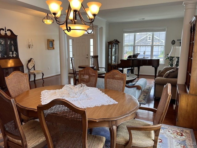 dining space with a chandelier, decorative columns, and hardwood / wood-style floors