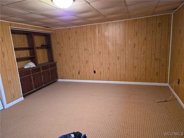 unfurnished bedroom with wood walls, carpet flooring, and a paneled ceiling