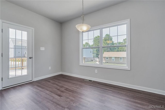 unfurnished dining area with dark wood-style flooring, visible vents, and baseboards