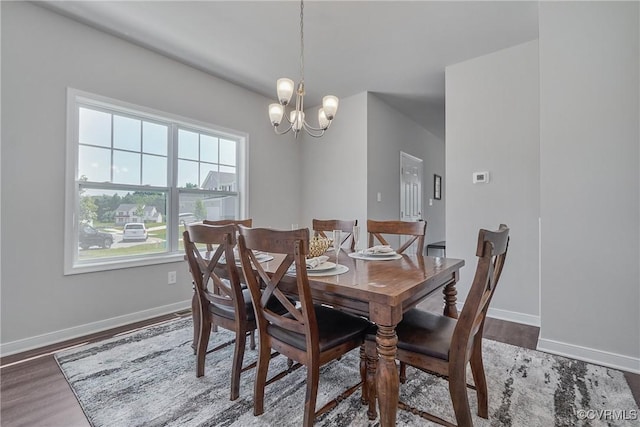 dining room with dark wood-style floors, a chandelier, and baseboards