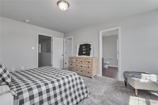 bedroom with ensuite bathroom, baseboards, and light colored carpet