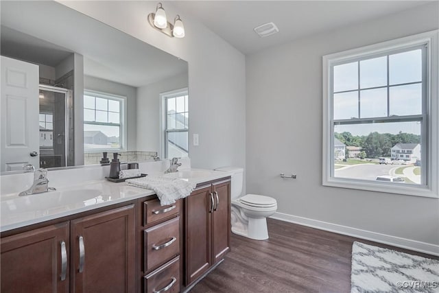 bathroom with toilet, wood finished floors, a sink, baseboards, and a stall shower