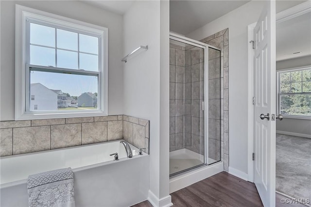 bathroom with a garden tub, wood finished floors, a shower stall, and baseboards