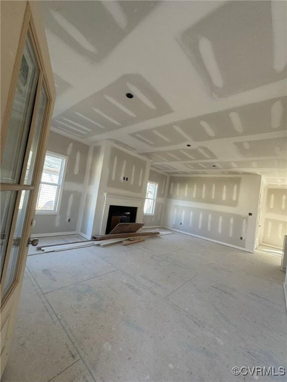 unfurnished living room featuring a fireplace with raised hearth