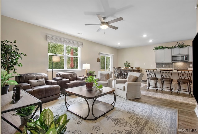 living room with wood-type flooring, ceiling fan, and a healthy amount of sunlight