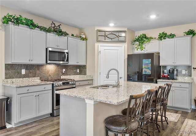 kitchen featuring a center island with sink, appliances with stainless steel finishes, dark wood-type flooring, and sink