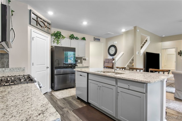 kitchen with dark wood-type flooring, sink, decorative backsplash, stainless steel appliances, and light stone countertops