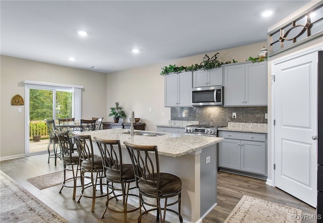 kitchen with gray cabinets, sink, an island with sink, appliances with stainless steel finishes, and dark hardwood / wood-style flooring