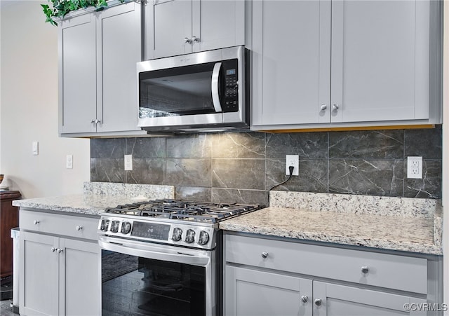 kitchen featuring light stone countertops, stainless steel appliances, and backsplash