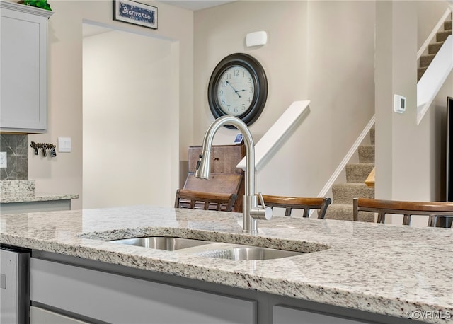 kitchen featuring white cabinets, light stone countertops, sink, and tasteful backsplash