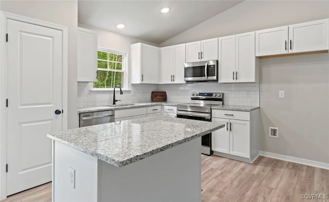 kitchen with lofted ceiling, a center island, white cabinets, and stainless steel appliances