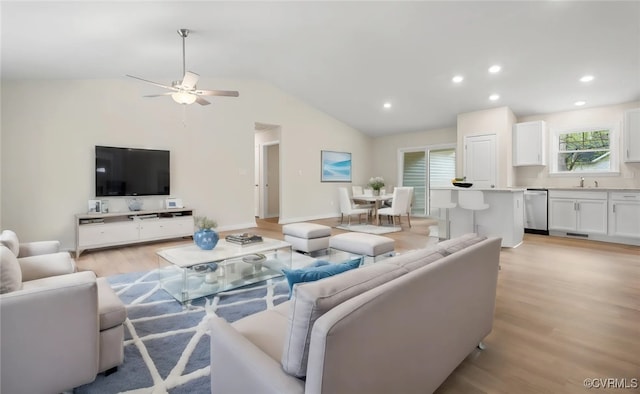 living room featuring sink, light hardwood / wood-style floors, and vaulted ceiling