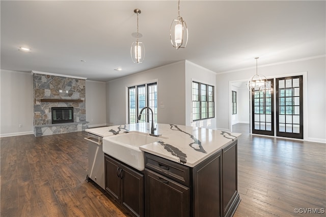 kitchen with pendant lighting, a center island with sink, a fireplace, and dark wood-type flooring