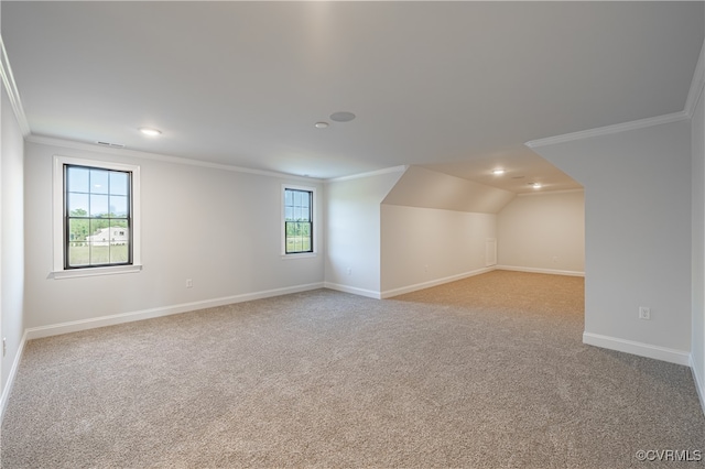 carpeted spare room with a wealth of natural light, vaulted ceiling, and crown molding