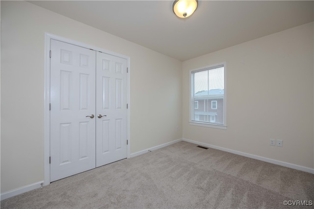 unfurnished bedroom with light colored carpet and a closet