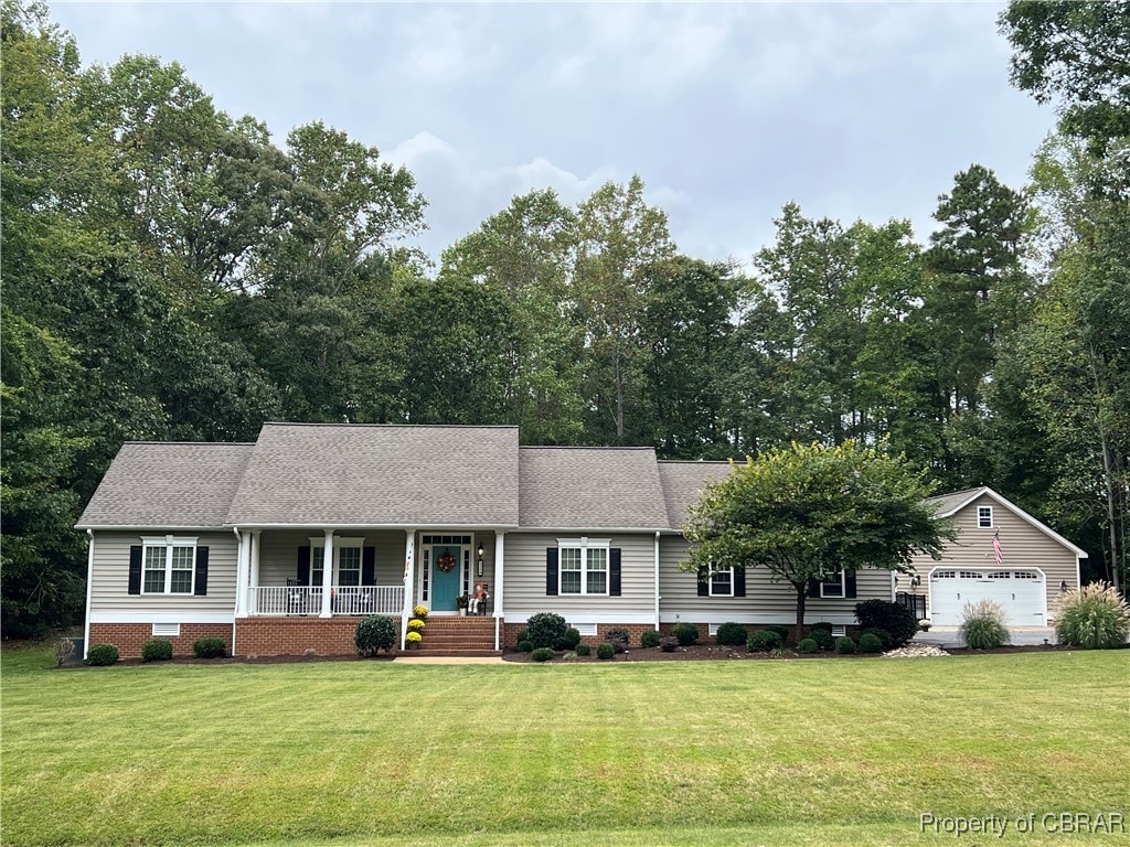 single story home featuring a garage, a front lawn, covered porch, and an outbuilding