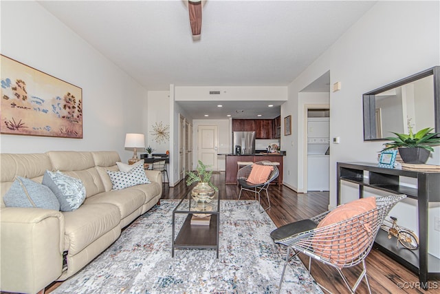 living room with stacked washer / dryer and dark hardwood / wood-style flooring