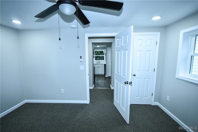 unfurnished room with ceiling fan and dark carpet