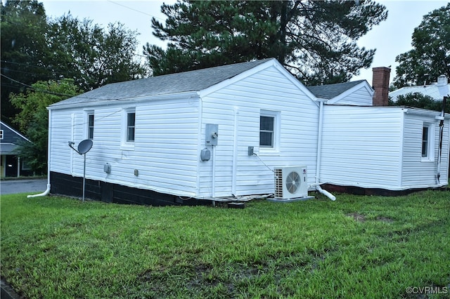 back of property featuring ac unit and a lawn