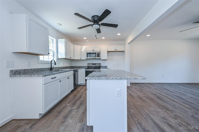 kitchen with stainless steel appliances, sink, a center island, dark hardwood / wood-style floors, and white cabinetry