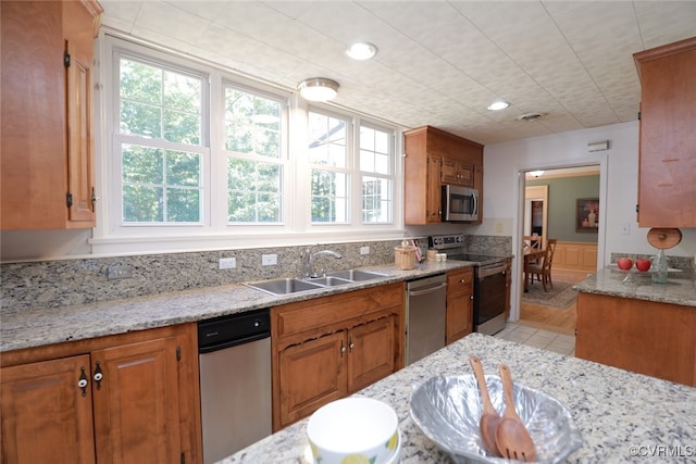 kitchen with light stone counters, sink, stainless steel appliances, and light hardwood / wood-style floors