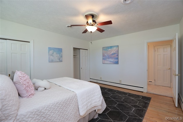 bedroom featuring hardwood / wood-style floors, a textured ceiling, baseboard heating, and ceiling fan