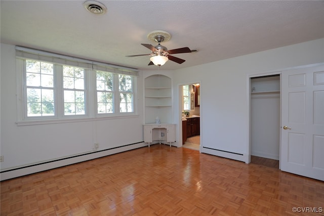 unfurnished bedroom with light parquet floors, ceiling fan, a textured ceiling, baseboard heating, and connected bathroom