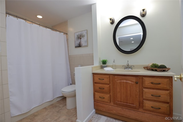 bathroom with tile patterned floors, vanity, toilet, and tile walls