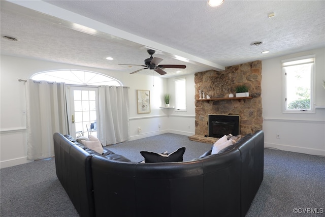 carpeted living room featuring ceiling fan, a fireplace, beamed ceiling, and a textured ceiling