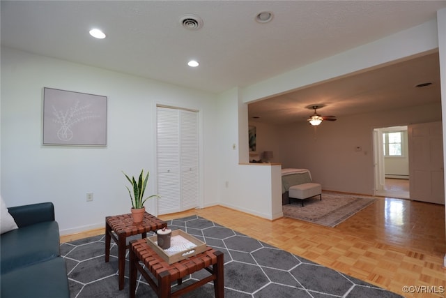 living room with ceiling fan, parquet flooring, and baseboard heating