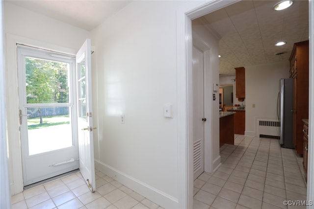 doorway to outside featuring light tile patterned flooring and radiator