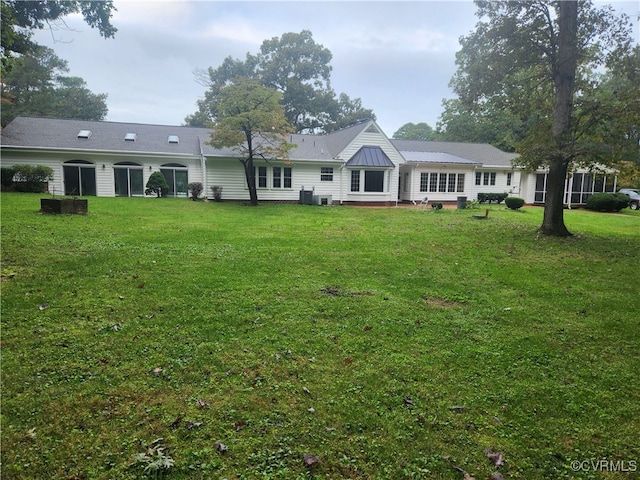 rear view of house featuring a lawn and central AC