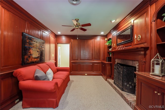 living room featuring ceiling fan, a fireplace, light colored carpet, and ornamental molding