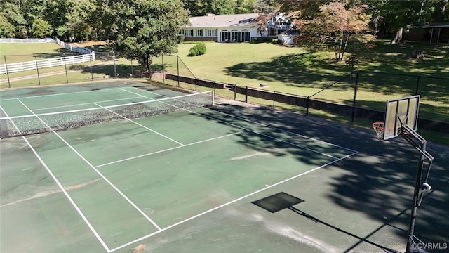 view of tennis court with a lawn and basketball hoop