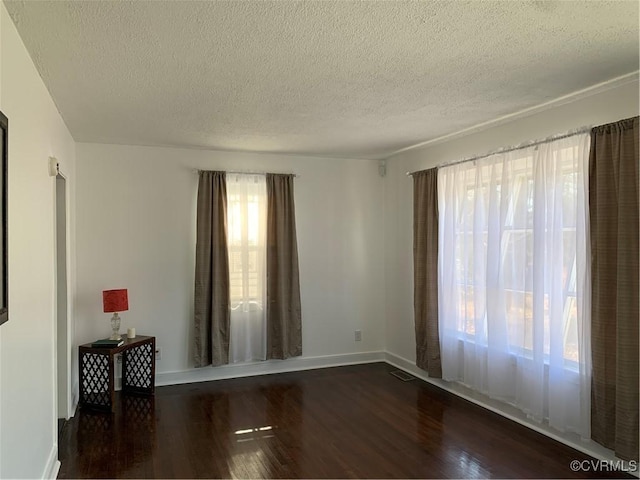 spare room featuring a textured ceiling and dark hardwood / wood-style flooring