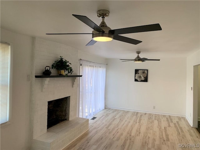 unfurnished living room with ceiling fan, light wood-type flooring, and a brick fireplace