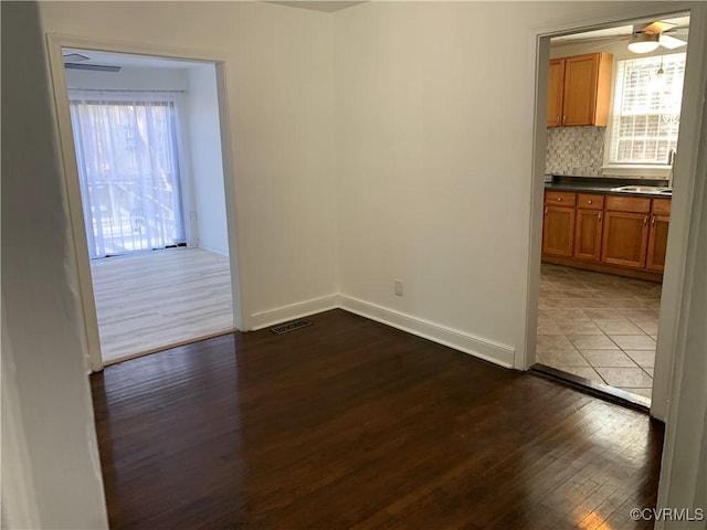 unfurnished dining area with wood-type flooring, ceiling fan, a healthy amount of sunlight, and sink