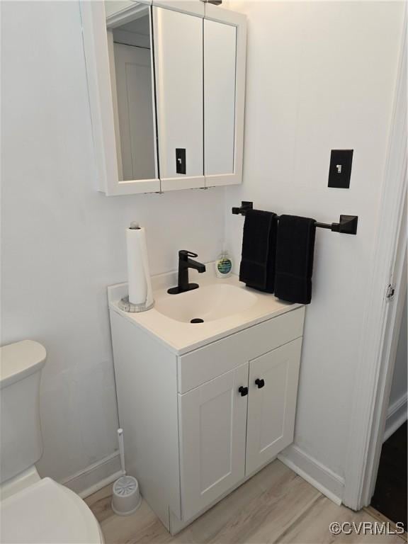 73 Henrico St, Petersburg, VA 23803 - half bath featuring toilet, baseboards, vanity, and wood finished floors